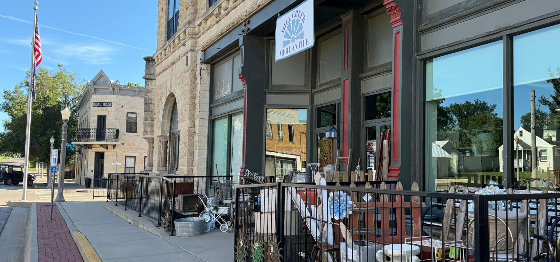 A storefront with a variety of items is displayed outside a historic building on a sunny day.