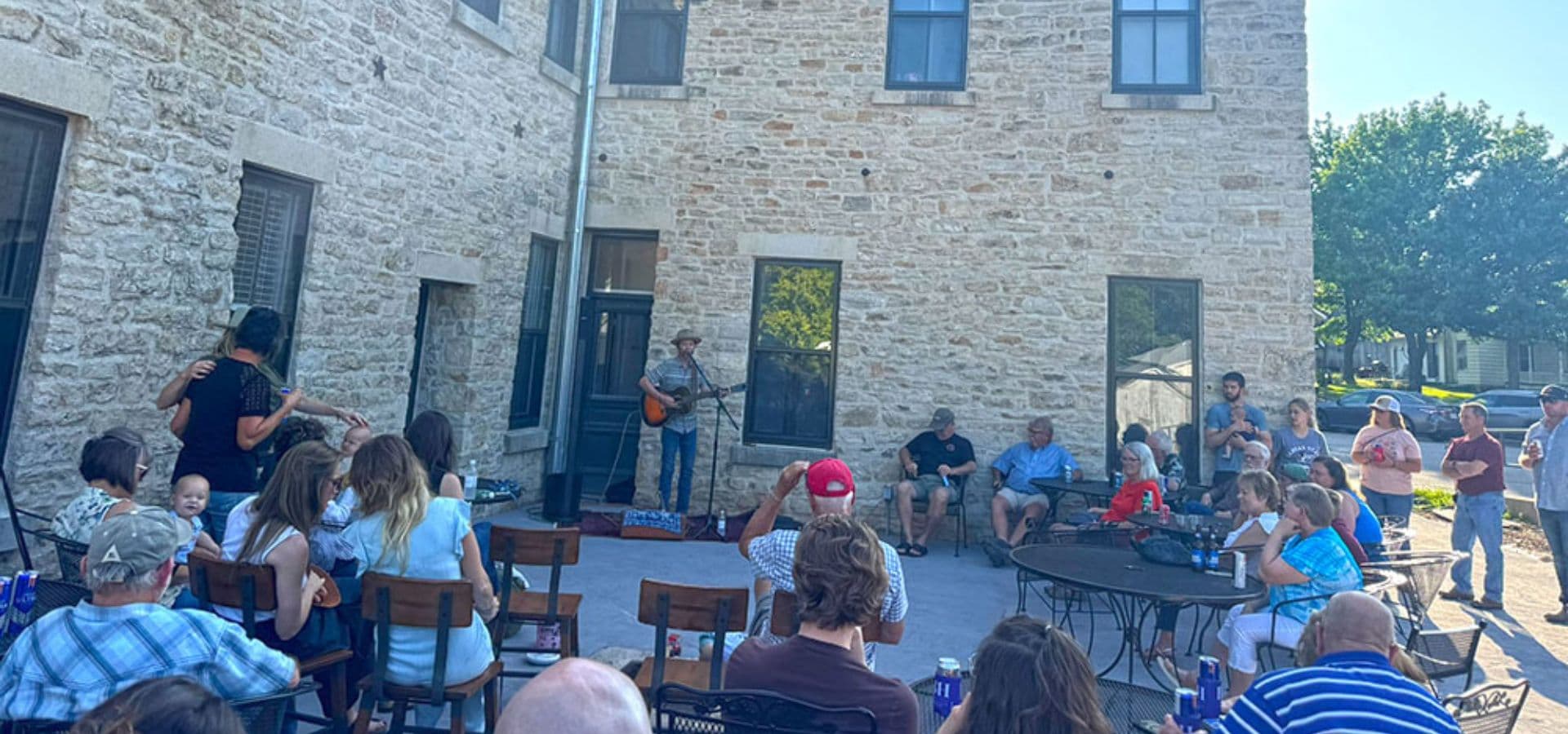 A crowd enjoying a live musical performance in a courtyard surrounded by stone buildings.