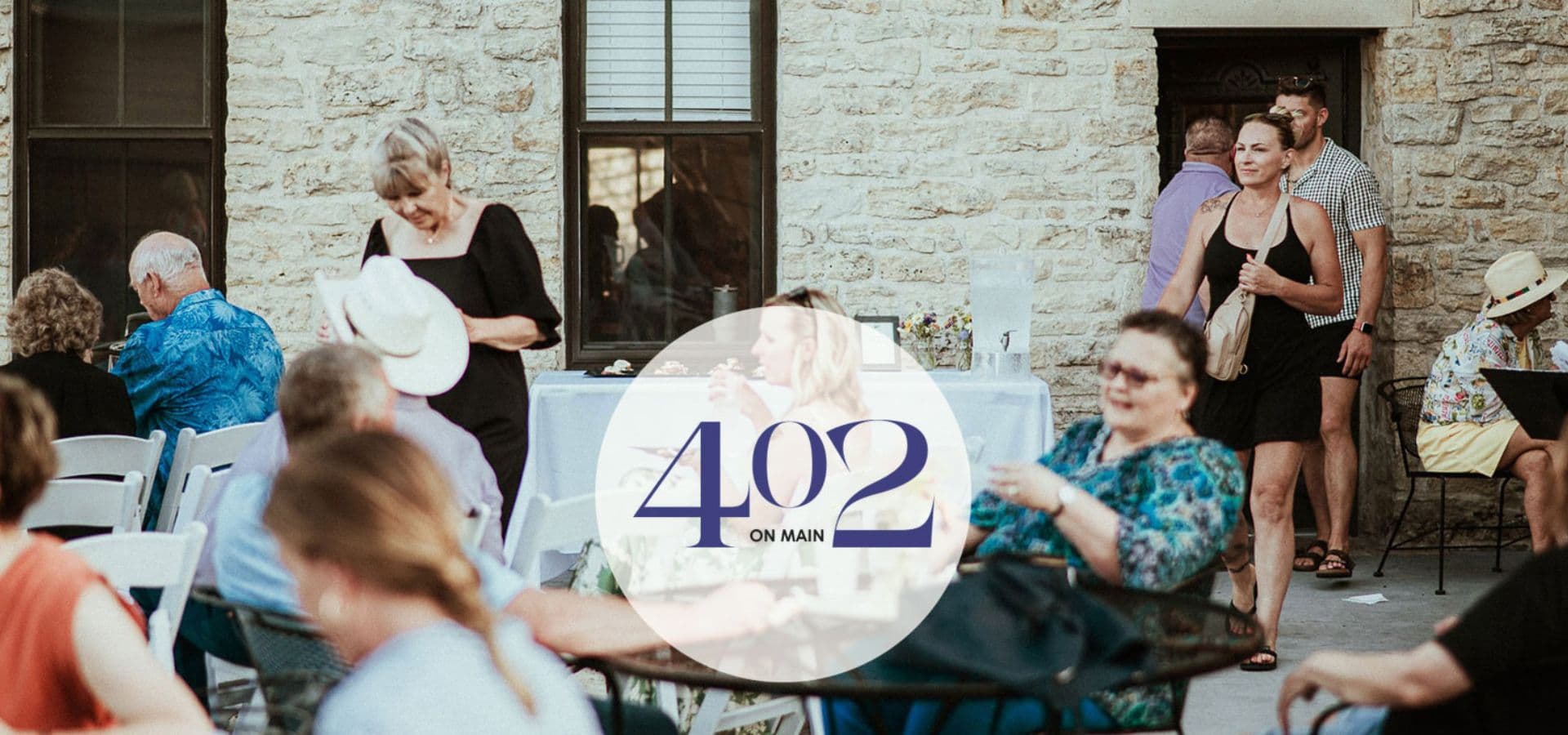 A lively outdoor gathering at 402 on Main featuring people socializing and dining.