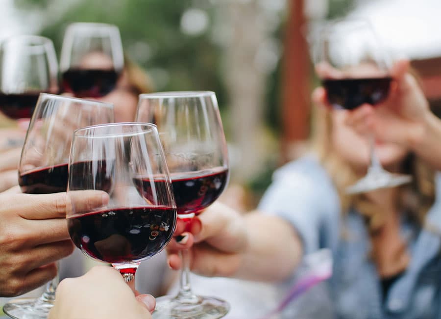 A group of people toasting with glasses of red wine.