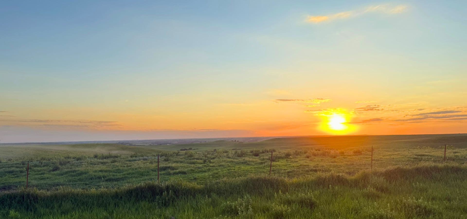 A vibrant sunset over a grassy landscape.