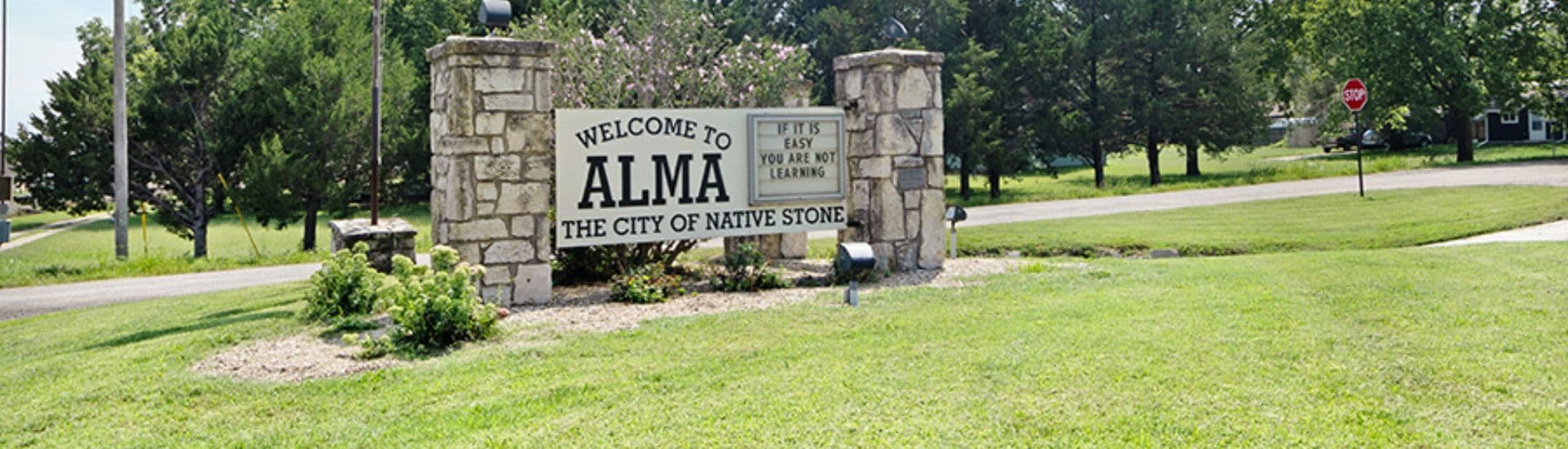Welcome sign for Alma, the "City of Native Stone," surrounded by greenery.