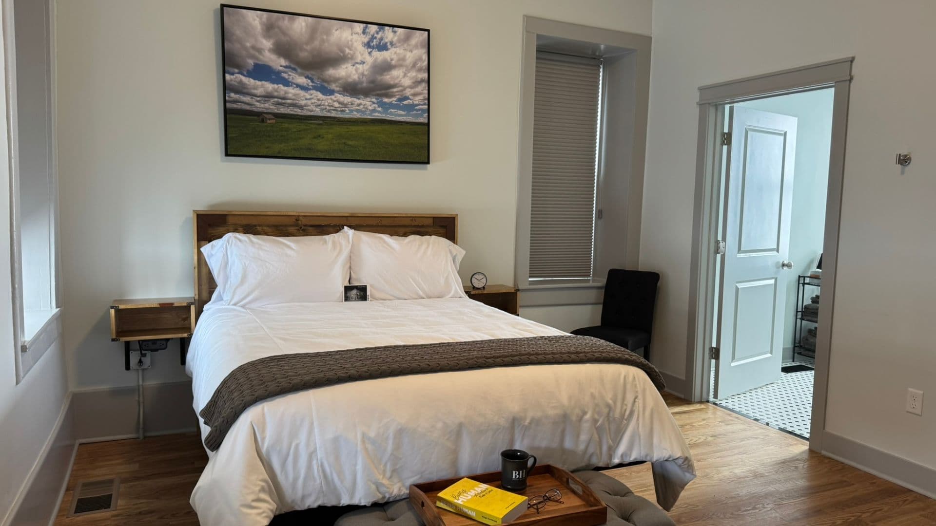 A cozy bedroom featuring a king-sized bed, a wooden nightstand, and an adjacent bathroom entrance.