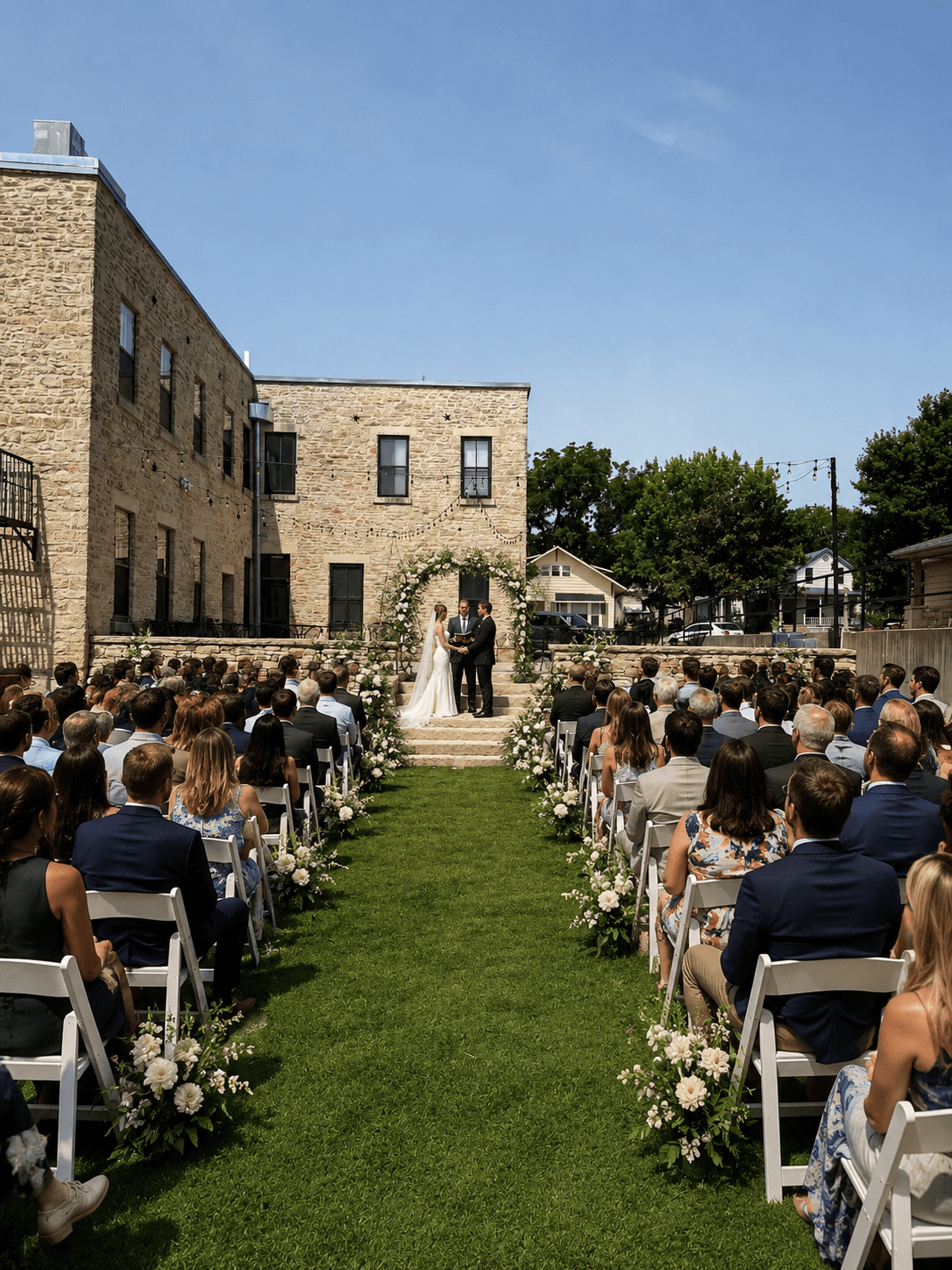 A couple exchanges vows during an outdoor wedding ceremony surrounded by guests.
